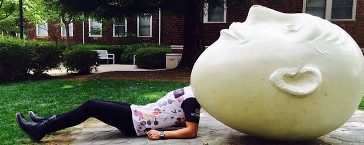 Picture of a man posing behind a UC Davis Egg Head art installation