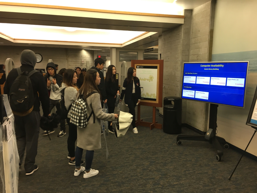 students viewing a chart that lists available computers in the UCSD Geisel Library