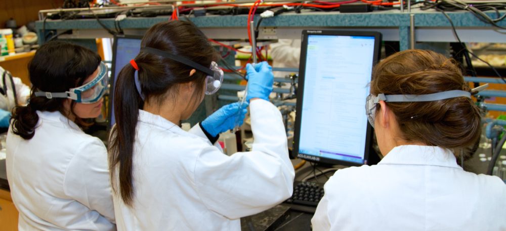 children working in a science lab, in front of a computer