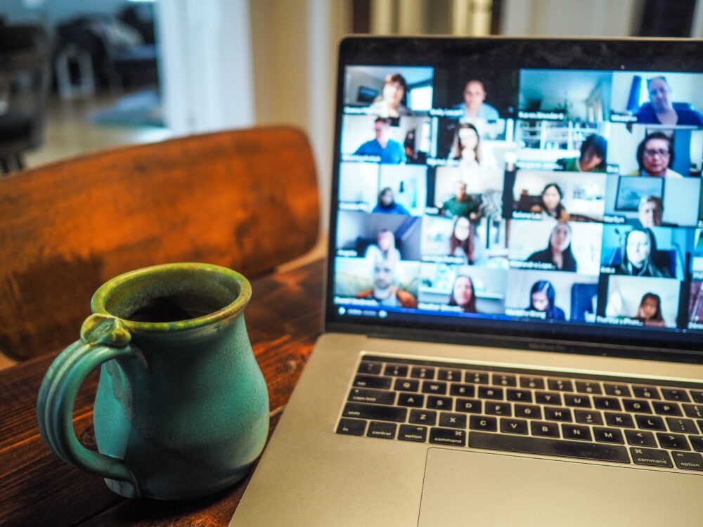 A coffee mug sitting next to a laptop, during a Zoom meeting