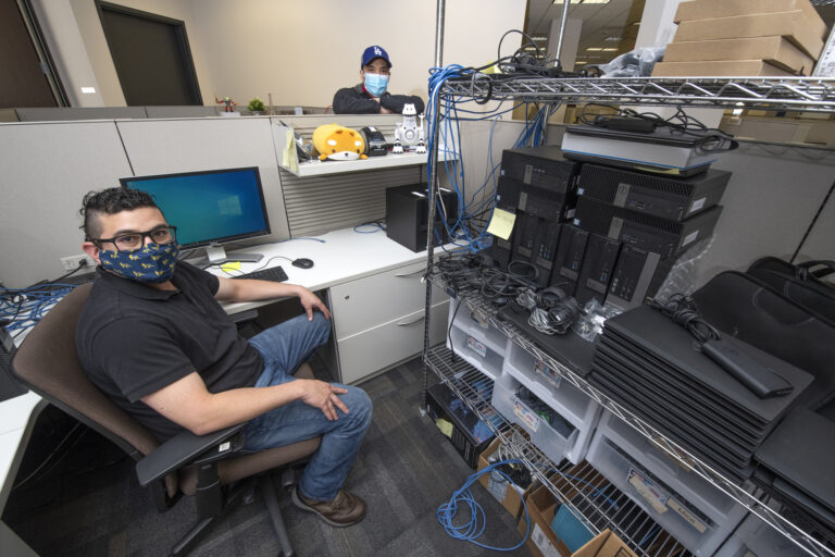 On-campus essential workers Matthew Tendroch (seated) and Justin Hsieh are from the UCI Office of Information Technology’s Wellness, Health & Counseling Services desktop support team, serving the Student Health Center. Steve Zylius / UCI