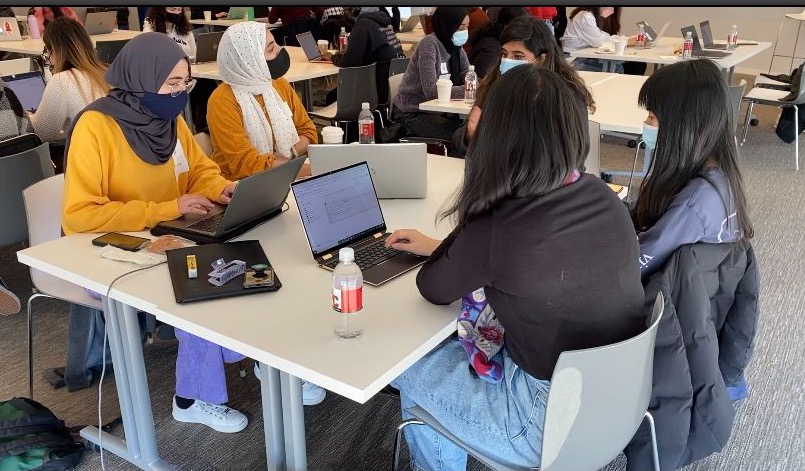 Five women work on computers