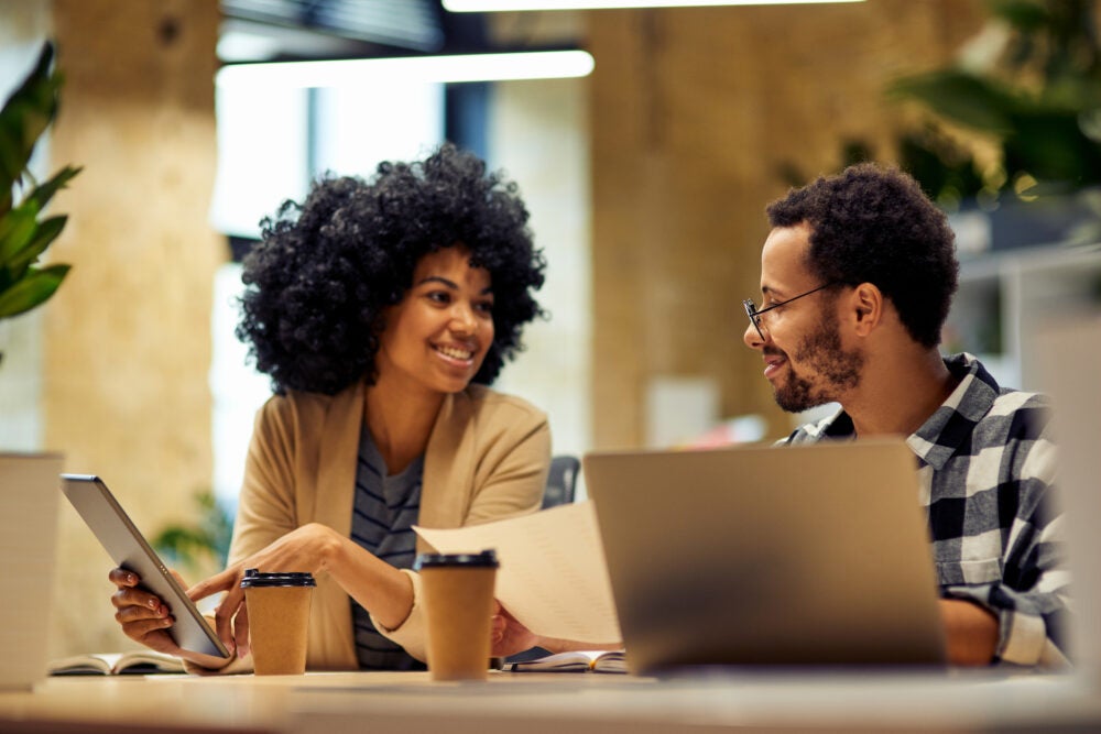 Sharing fresh ideas. Two people sitting at desk and communicating while working together in coworking space. Office life, teamwork and business