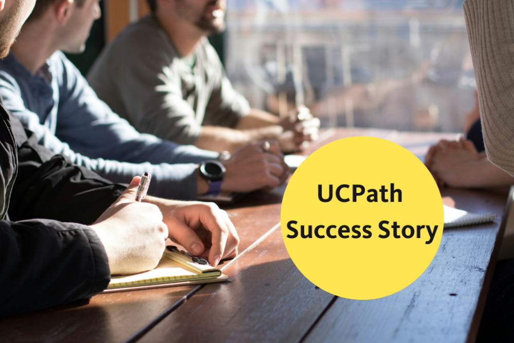 Photo of people collaborating around a desk - UCPath success story in text