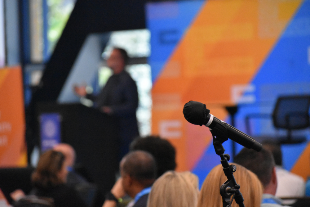 Photo of speaker blurred with microphone in the foreground at Cyber Security Summit