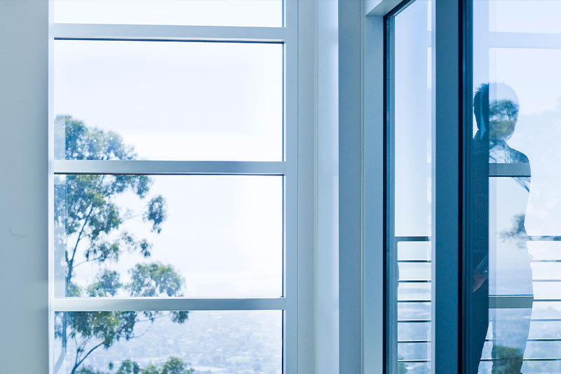 Blue photo of a window with a shadow of a person on the right.