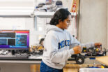 Amrita Mohandas, a 2023 CITRIS Workforce Innovation intern, adjusts a four-wheeled robot used for forestry research in UC Merced professor Ricardo de Castro's laboratory."